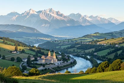 Vue panoramique lumineuse de Lourdes depuis les hauteurs, avec le sanctuaire Notre-Dame de Lourdes, le Gave de Pau et les montagnes pyrénéennes en arrière-plan.